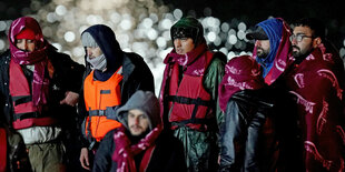 Menschen in Rettungswesten stehen in der Nacht zusammen