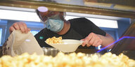 Eine Frau bereitet in einem Kino Popcorn zu