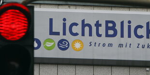 Rote Ampel vor einem Firmenschild mit der Aufschrift "Lichtblick - Strom mit Zukunft""