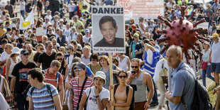 DemonstratInnen gegen die Coroapolitik halten ein Porträt von Sucharit Bhakdi "Danke" in die Höhe