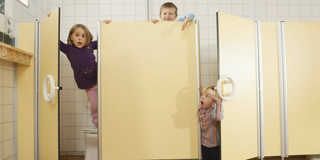 Drei Kinder spielen in einer öffentlichen Toilette