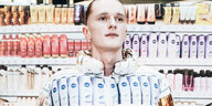Ein Mensch steht vor einem Regal mit Körperpflegeprodukten, er trägt eine Jacke, auf denen Nivea-Flaschen zu sehen sind