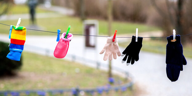 Fünf verschiedene Handschuhe hängen auf einer Leine