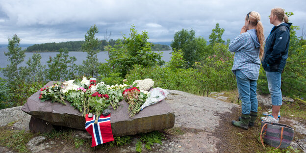 Frauen stehen neben einer Gedenkstätte mit Blick auf eine Insel