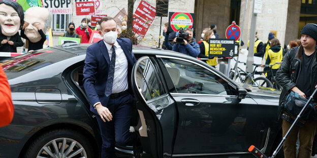 FDP-Generalsekretär Wissing steigt aus einem Dienstwagen aus, im Hintergrund Demonstrierende