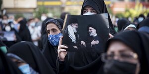 Verschleirte Islamistinnen halten ein Poster von Ayatollah Khamene und Ebrahim raisi in die Höhe