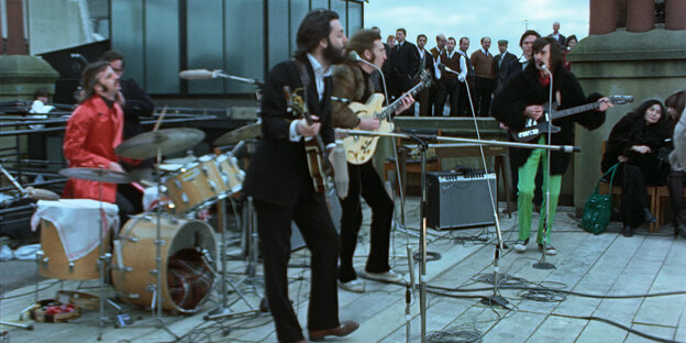 Die Beatles spielen auf einem Hausdach Musik