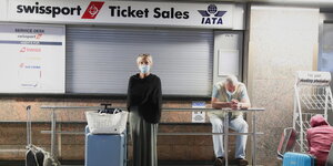 Passagiere warten vor einem geschlossenen Flughafenschalter.