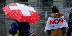 Im Schneeregen steht eine Frau mit einem "Non"-Transparent