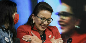 Xiomara Castro, im roten Blazer, verschränkt die Arme vor der Brust und lächelt
