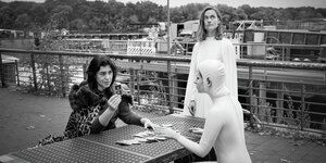 Drei Frauen legen Karten an einem Bootsanleger