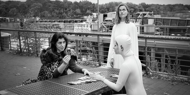 Drei Frauen legen Karten an einem Bootsanleger