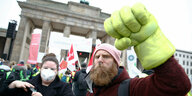 Fetter gelber Handschuh mit erhobener Faust, bärtiger Demonstrant vor Brandenburger Tor