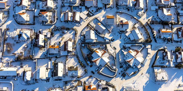 Von Schnee bedeckte Einfamilienhäuser aus der Luft fotografiert.