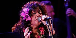 Maria Muldaur singt , schließt die Augen und hat eine rosa Blume im Haar