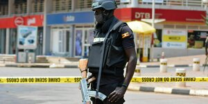 Ein Uniformierter mit Waffe vor einem Absperrband.