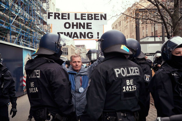 Polizisten und ein Demonstrant mit Plakat.