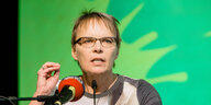 Anja Hajduk hinter einem Mikrofon vor einer grünen Wand
