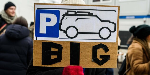 Schild von DemonstrantIn zeigt SUV und "BIG"