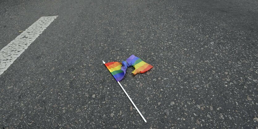 Ein angekokeltes Regenbogenfähnchen liegt auf de rStraße.