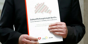 Das Foto zeigt den rot-grün-roten Koalitionsvertrag in den Händen von Linkspartei-Senator Klaus Lederer.