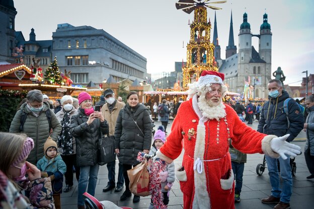 Ein Weihnachtsmann auf einem Weihnachtsmarkt mit Menschen.