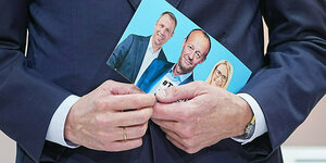 Detailfoto, Friedrich Merz hält einen Flyer mit einem Foto seines Teams in den Händen