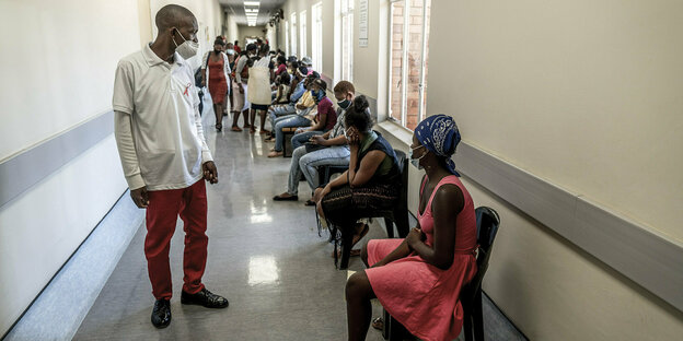 Menschen sitzen in einme flur und warten auf ihre Impfung