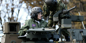 Premier Kishida (mit Helm) schaut aus dem Geschützturm eines Panzers.