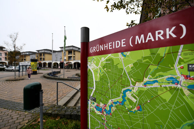 Auf einem Platz steht ein Schild mit dem Lageplan von "Grünheide (Mark)"