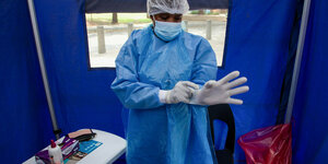 Südafrika, Soweto: Ein Mitarbeiter des Gesundheitswesens bereitet sich darauf vor, eine Person in einer Einrichtung auf COVID-19 zu testen.