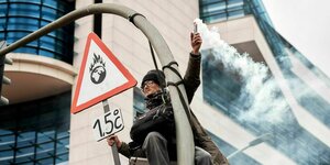 Vor dem Willy Brandt Haus ist ein Demonstrant die Straßenlaterne hochgeklettert, er hält ein Warnschild mit 1,5 Grad