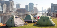 An einem Spreeufer stehen Zelte von Obdachlosen - im Hintergrund auf der anderen Spreeseite ist das Investorenprojekt Mediaspree zu sehen
