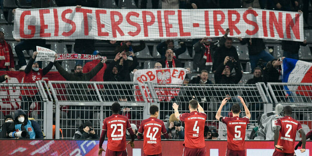 Profis des FC Bayern München stehen vor der Tribüne und klatschen Fans zu