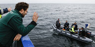 Jan Philipp Albrecht lehnt sich über eine Reling und beobachtet Männer in einem Schlauchboot