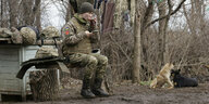 Eine Soldatin sitzt auf einem Baumstumpf und trinkt Tee.