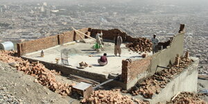 An einem Hang von Kabul arbeiten Männer beim Hausbau