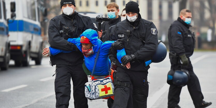 Polizisten tragen eine Person.