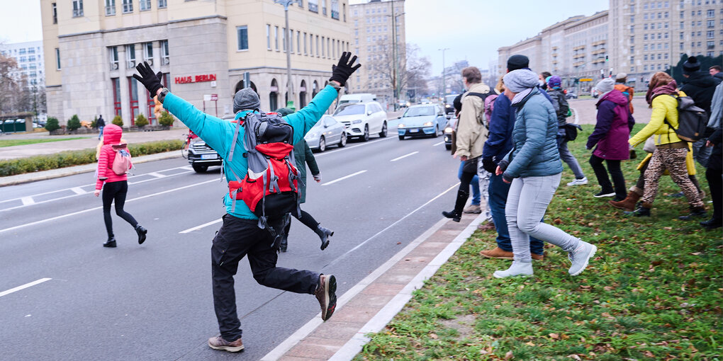 Eine Gruppe Querdenker:innen rennt vom Mittelstreifen auf eine Straße