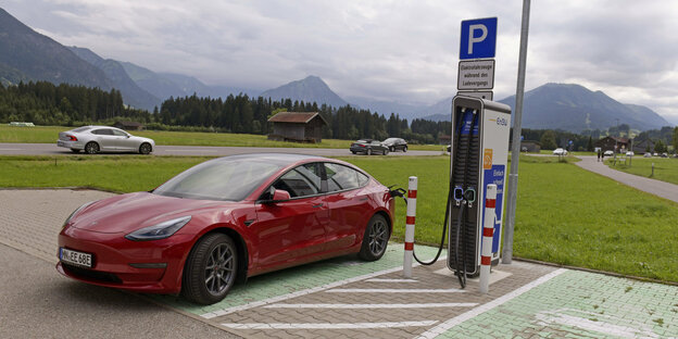 Ein Tesla an einer Ladestation vor Bergen.