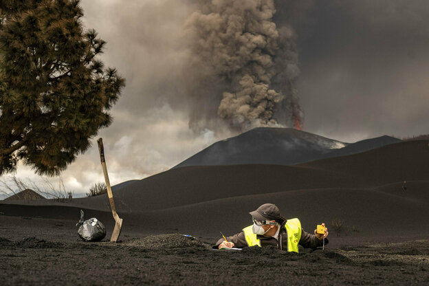 Vulkan auf La Palma spuckt Asche. Im Vordergrund sammelt ein Forscher Ascheproben.