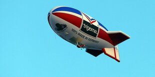 ein Zeppelin fliegt vor blauem Himmel, er trägt die Aufschrift Trigema