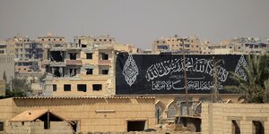 Häuser und ein Schwarz-weißes Banner mit arabischen Schriftzeichen