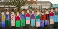 Pappfiguren hängen am Zaun iner Grundschule