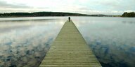 Eine Frau steht auf einem langen Steg an einem See in Finnland