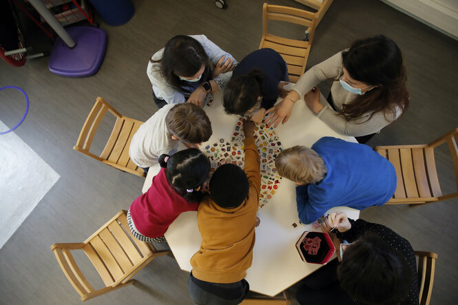 Einige Kinder sitzen an einem Tisch und stecken die Köpfe zusammen