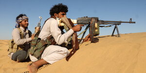 Zwei Männer mit Waffen in der Wüste.