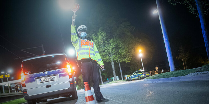 Polizist stoppt verkehr mit Kelle im Dunkeln.