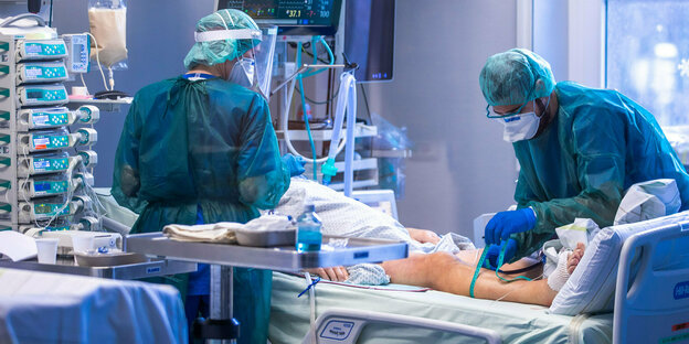 Eine Person liegt in einem Klinikbett umgeben von zwei Mediziner:innen