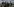 Ein Mann kontrolliert Dokumente dreier Männer, im Hintergrund ein Grenzübergang